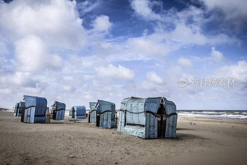 蓝色的沙滩椅子在Egmont aan Zee的北海海岸，荷兰在一个戏剧性的天空下